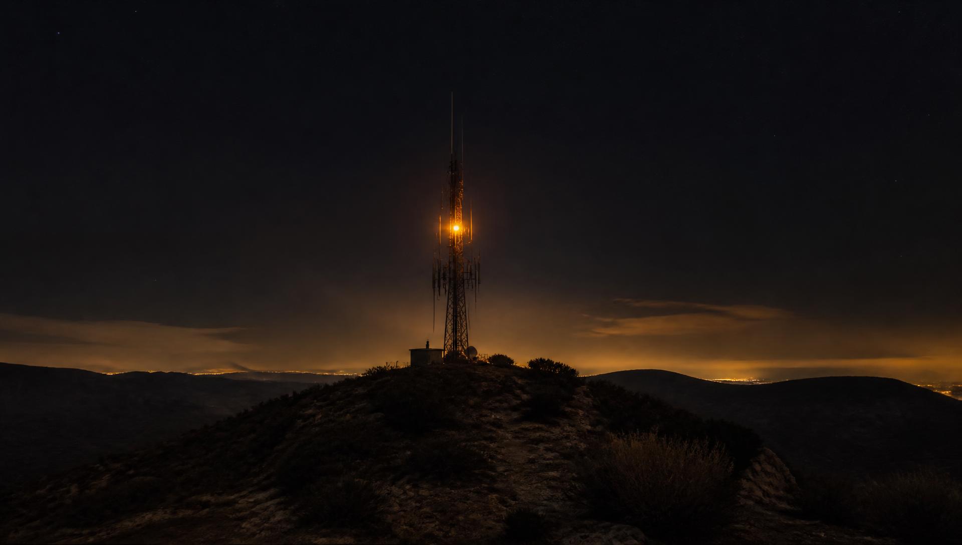 Radio repeater tower silhouetted against a dusk sky with antenna arrays